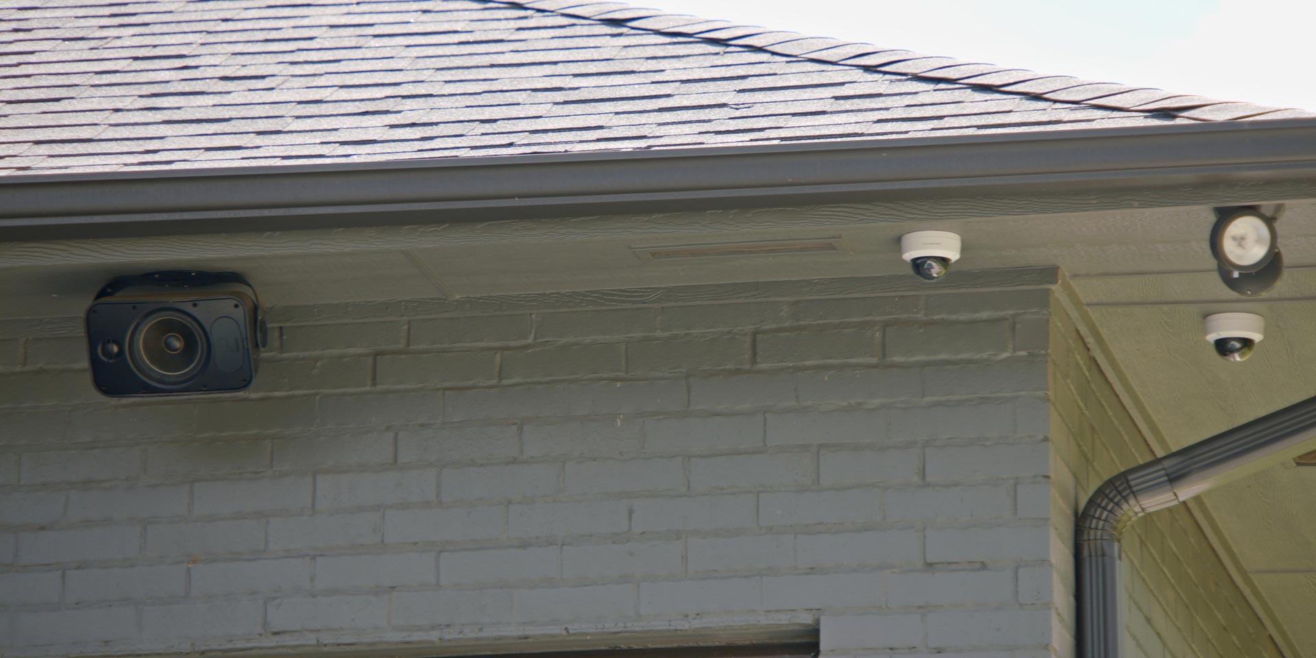 Outdoor security cameras and speakers installed under a home's eaves