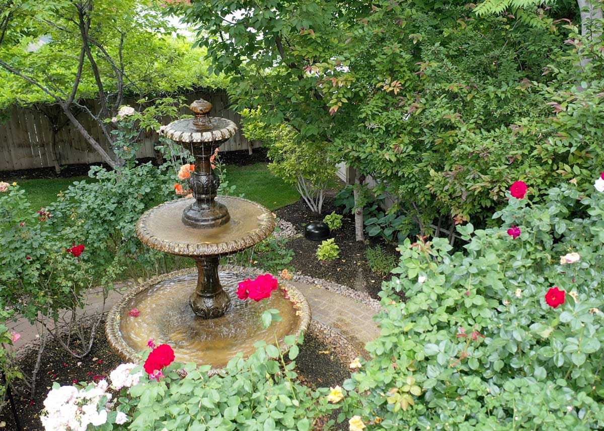 Garden fountain surrounded by blooming flowers and lush greenery