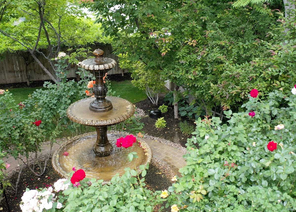 Garden fountain surrounded by blooming flowers and lush greenery