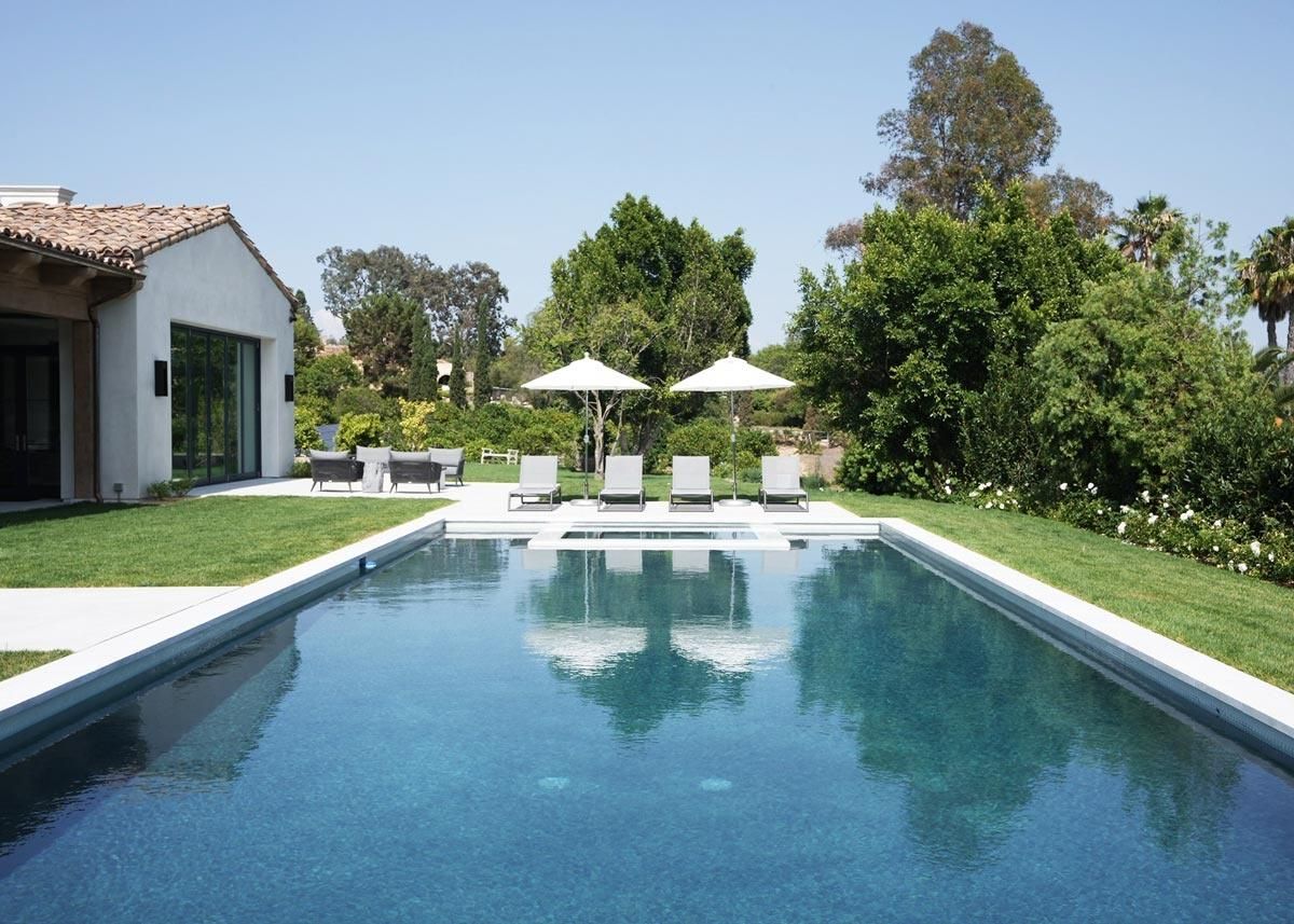 Backyard pool with a guesthouse, lounge chairs, and water features