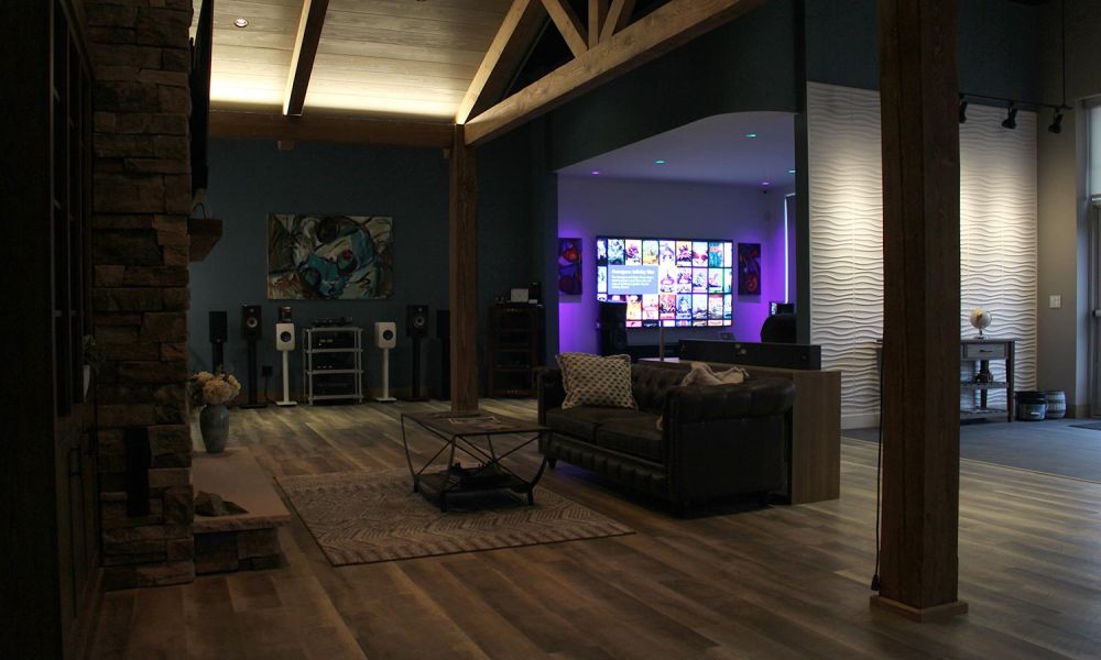 Cozy lounge area with stone fireplace, exposed beams, and large media screen