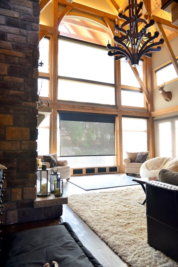 Living room with timber frame windows, high ceilings, and a lowered projection screen