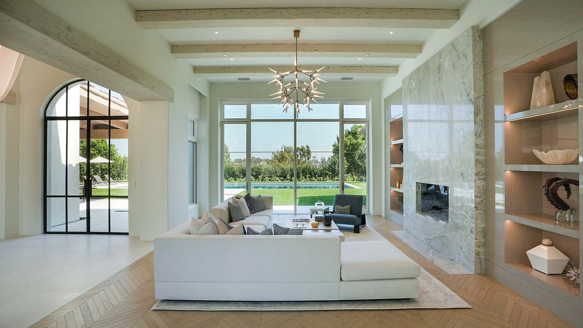 Modern living room with large windows, marble fireplace, and elegant lighting