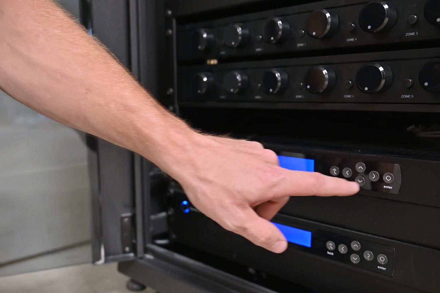 Hand adjusting controls on a rack-mounted AV system
