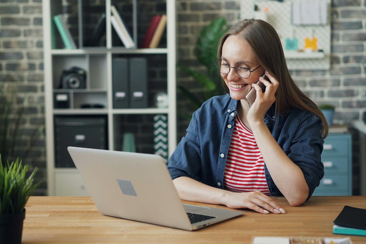 Woman smiling while talking on the phone at a desk