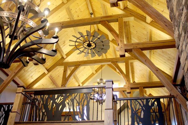 Vaulted timber ceiling with windmill-style fan and custom wrought iron railing