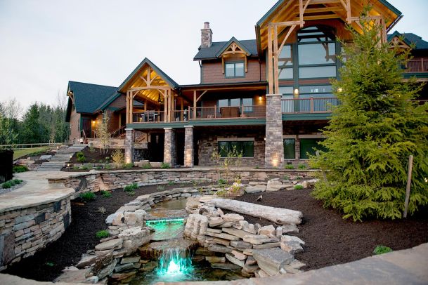 Large luxury timber-frame home with stone exterior and landscaped front yard