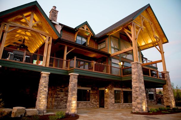Timber-framed house with stone columns and lit gable roofs at twilight