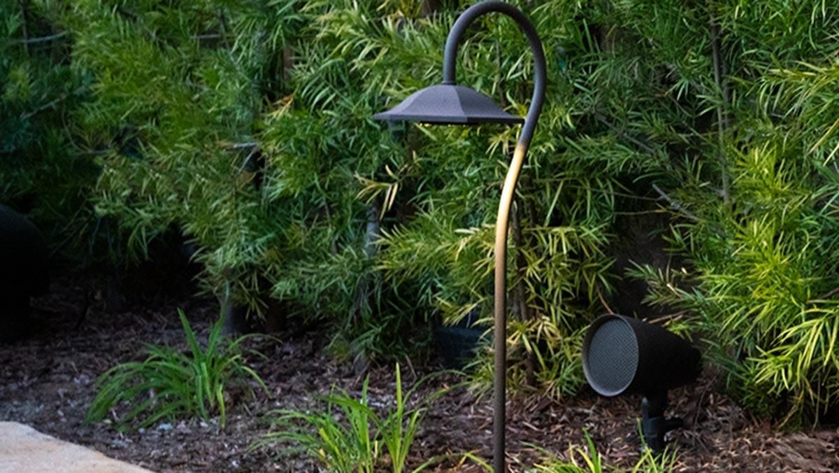 Outdoor landscape light with a built-in speaker among greenery