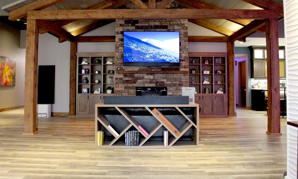 Wide view of showroom with angled bookshelves, stone fireplace, and vaulted ceiling