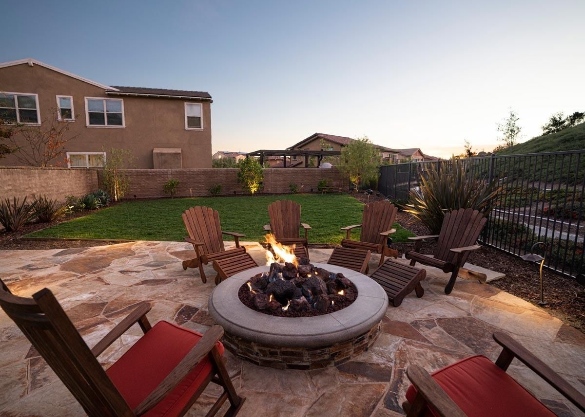Cozy outdoor fire pit seating area at sunset with Adirondack chairs