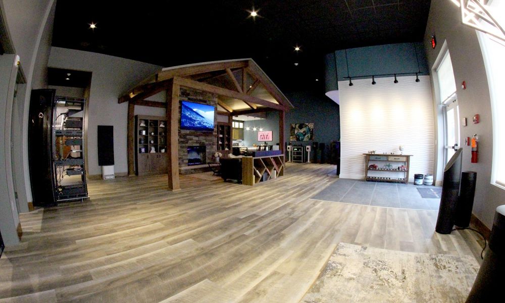 Wide view of showroom with angled bookshelves, stone fireplace, and vaulted ceiling