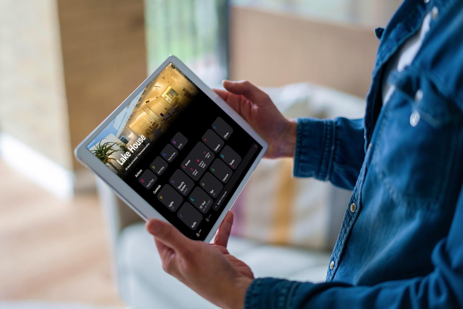 Person holding a tablet displaying a smart home interface