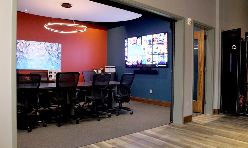 Conference room with mesh chairs, circular LED light, and wall-mounted screen