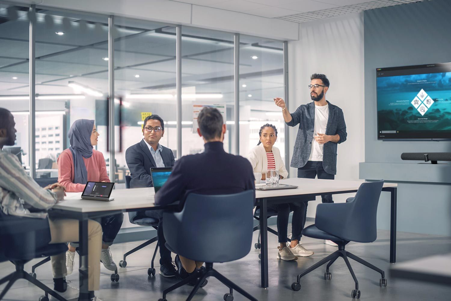 Man leading a business meeting with a presentation on a screen
