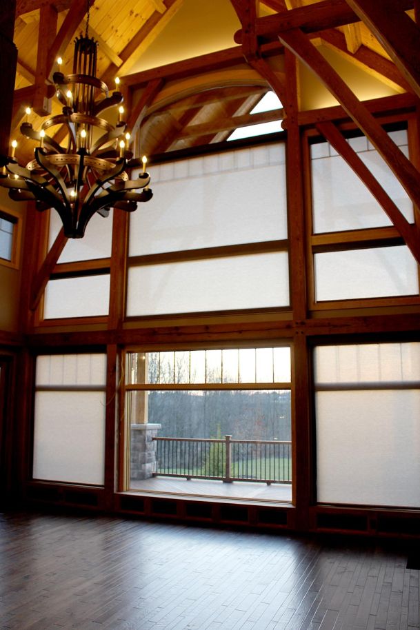 Empty great room with vaulted ceiling, chandelier, and tall window shades