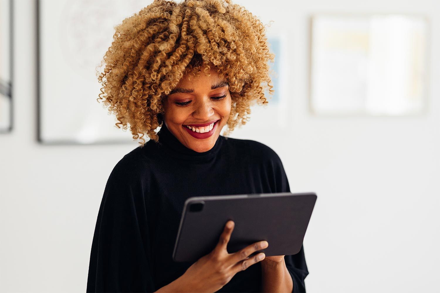Smiling woman holding a tablet in a well-lit indoor setting