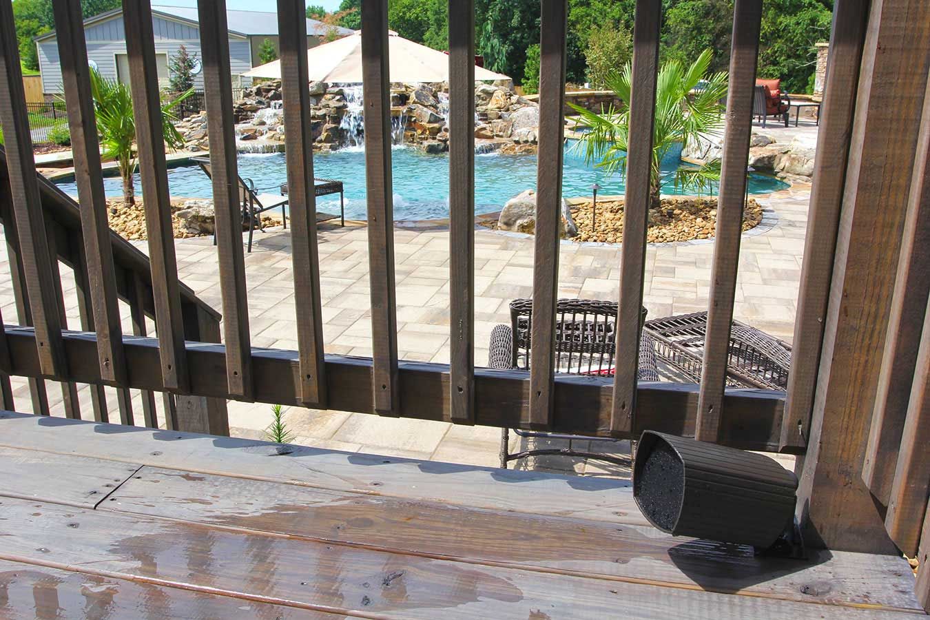 Outdoor deck with a landscape speaker and a poolside waterfall view