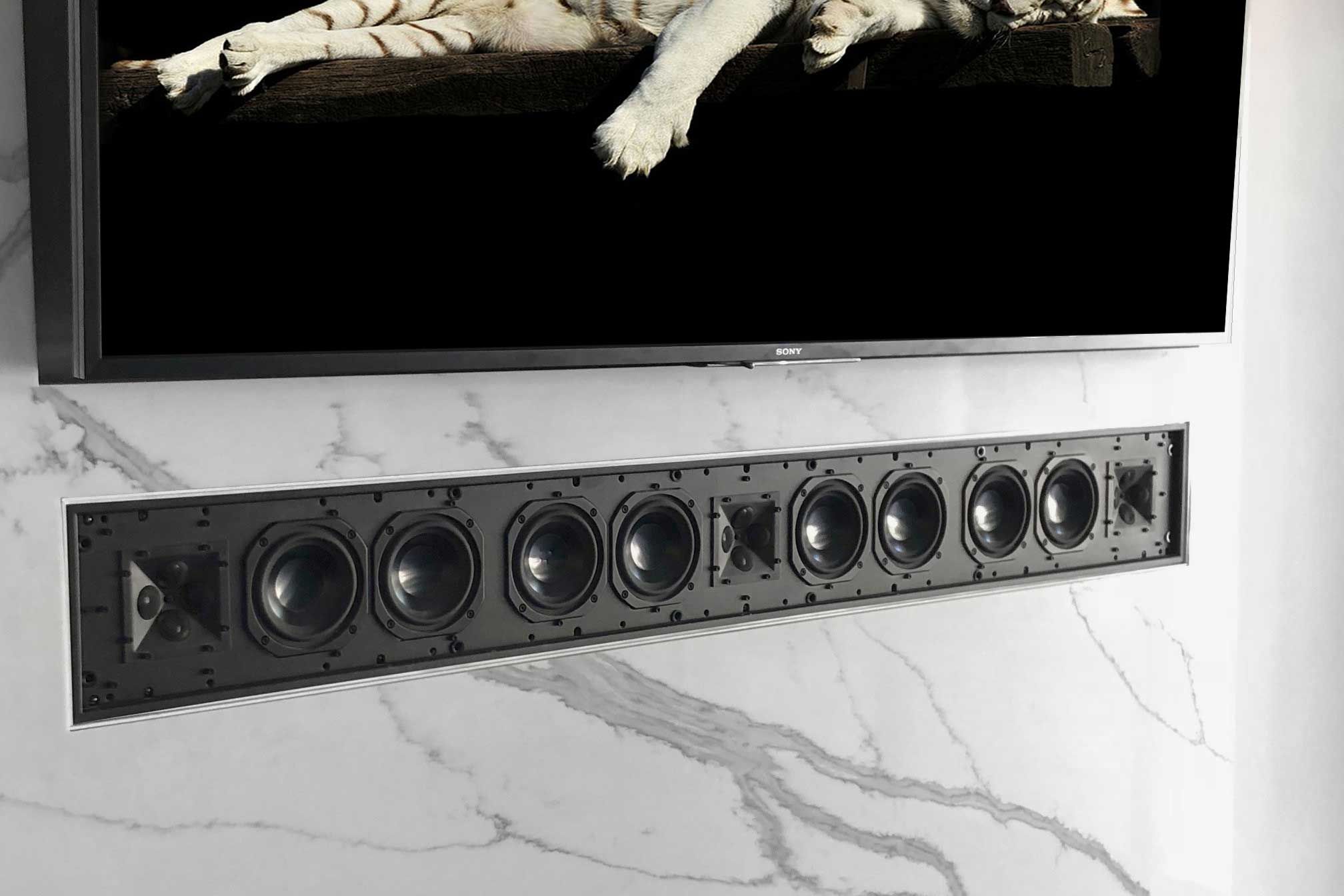 In-wall soundbar speaker installed below a TV on a marble wall