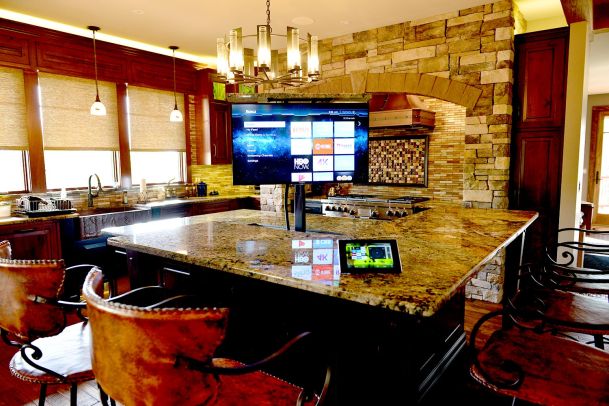 High-end kitchen with stone island and a retractable TV display showing streaming apps